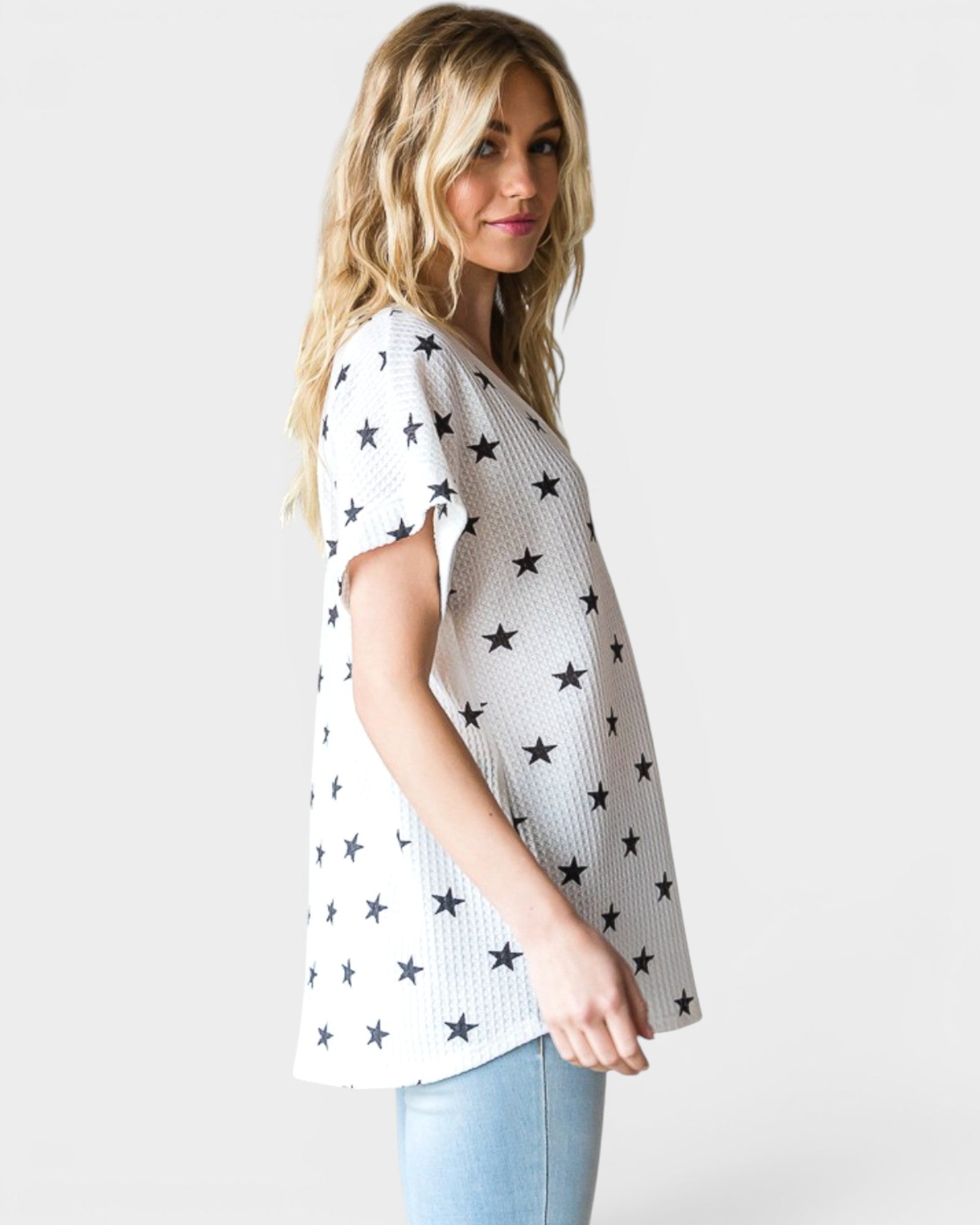 Woman wearing a white sweater with black star patterns on a plain background