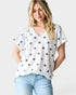 Woman wearing a white top with star patterns and light blue jeans on a plain background