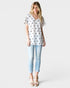 Woman wearing a white star-patterned top and light blue jeans on a white background