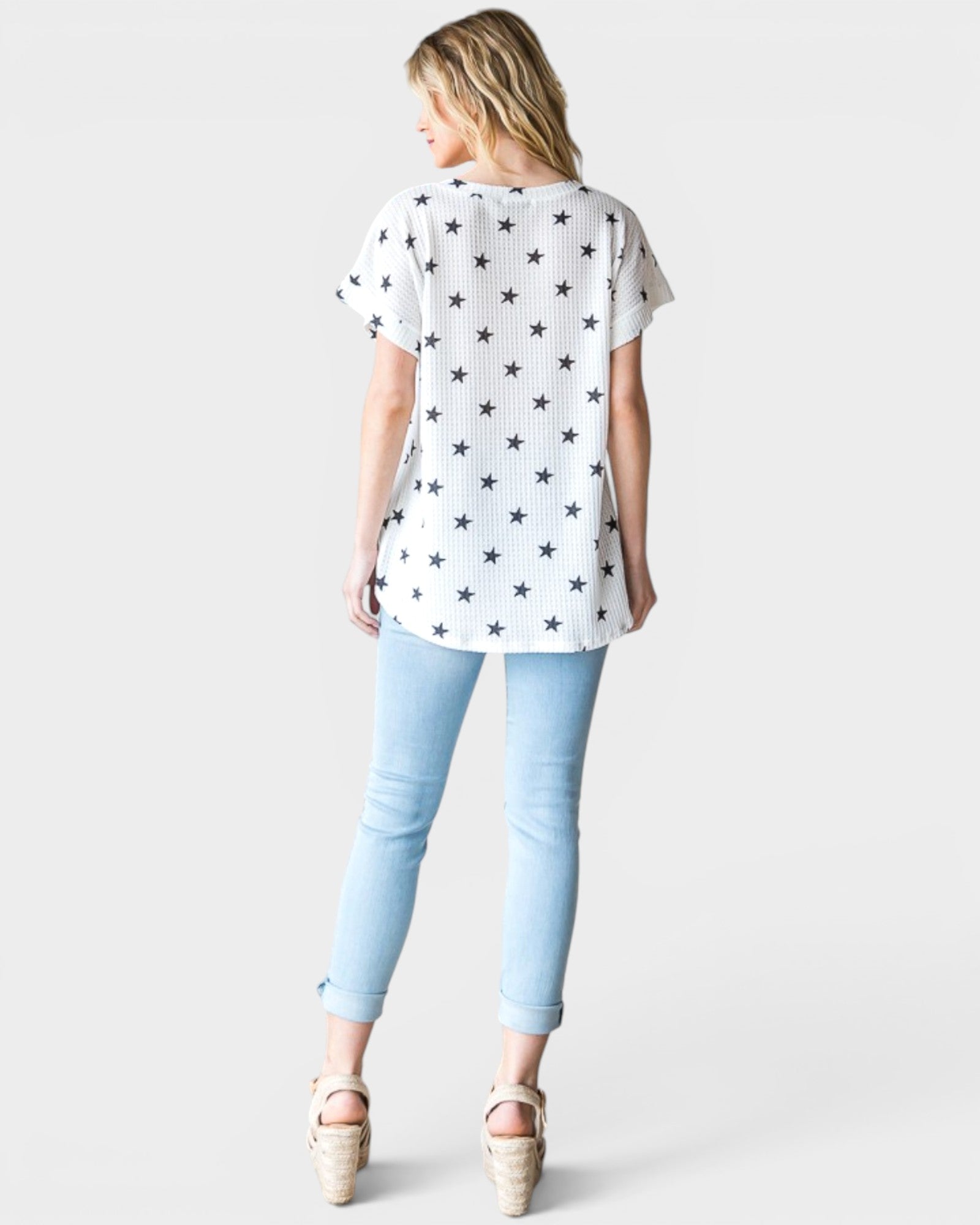 Woman wearing a white t-shirt with star pattern and light blue jeans on a white background
