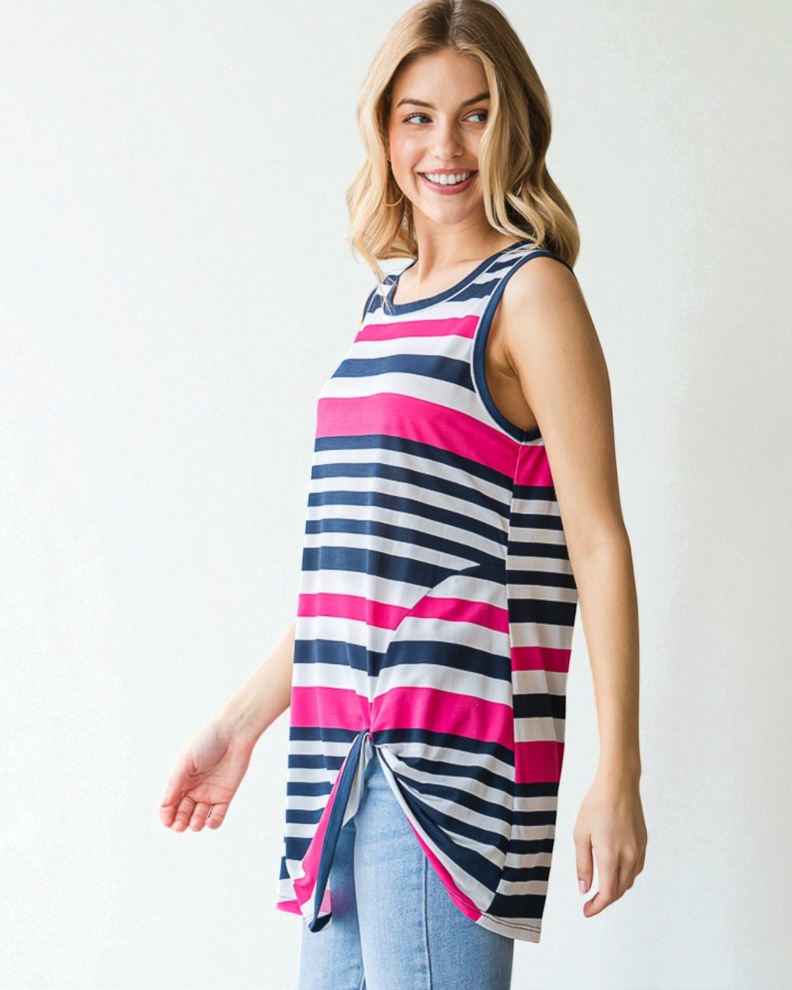Woman wearing a sleeveless striped top with pink and navy horizontal stripes on a white background