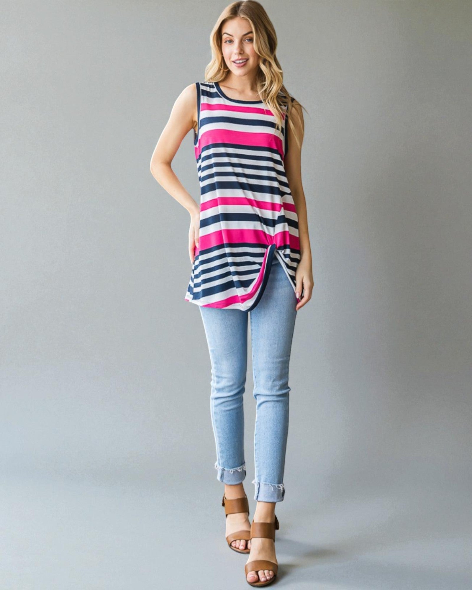 Woman wearing a striped tank top and jeans against a plain background