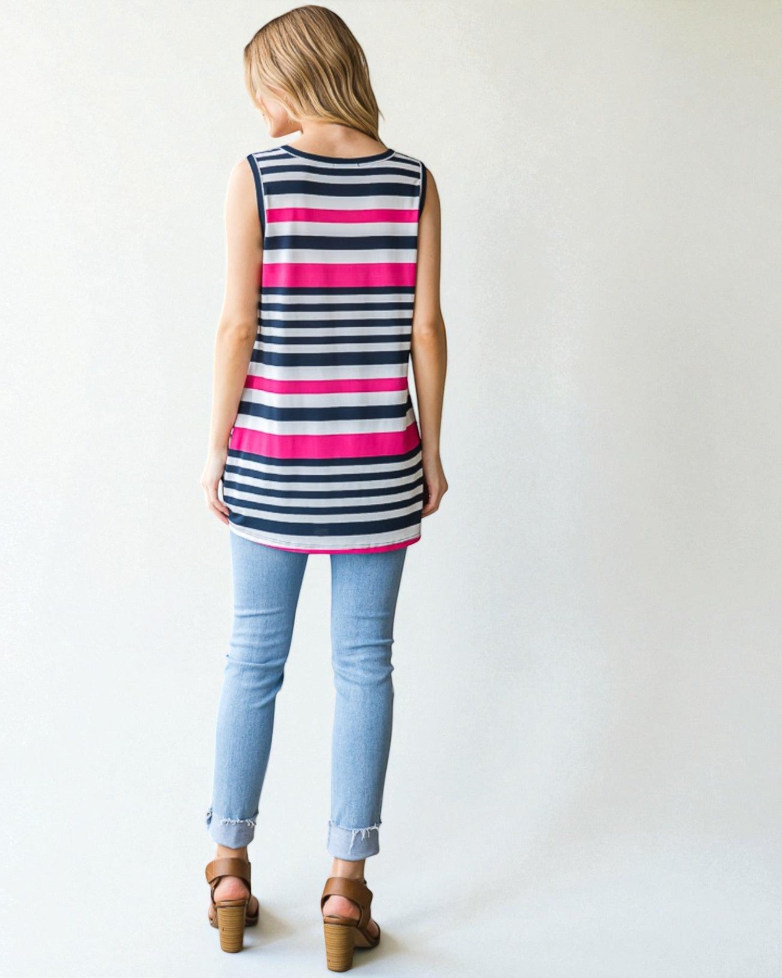 Woman wearing a sleeveless striped shirt and light blue jeans on a white background