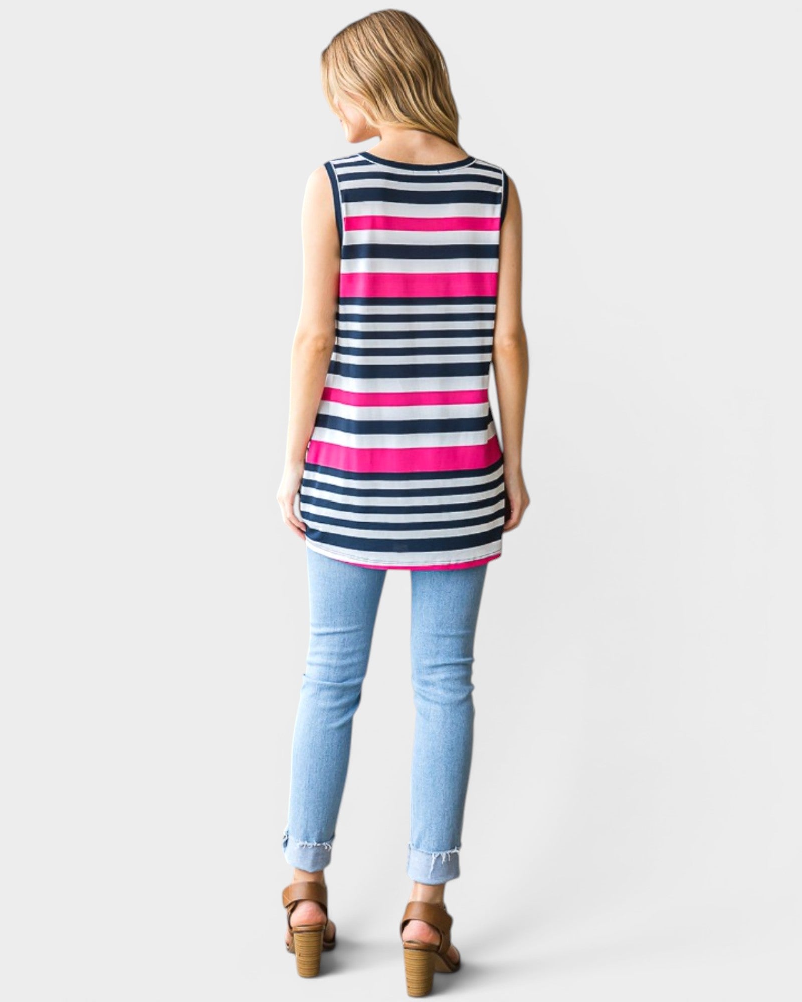 Woman wearing a sleeveless striped shirt and light blue jeans on a white background