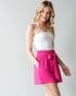 Woman wearing a white top and pink skirt on a plain background