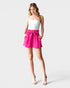 Woman wearing a white top and pink shorts on a light gray background