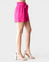 Person wearing a bright pink skirt with a tie waist on a light gray background