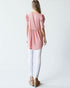 Woman wearing a pink dress with puffed sleeves and white pants on a plain background