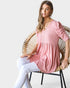 Woman wearing a pink top sitting on a wicker chair against a white background