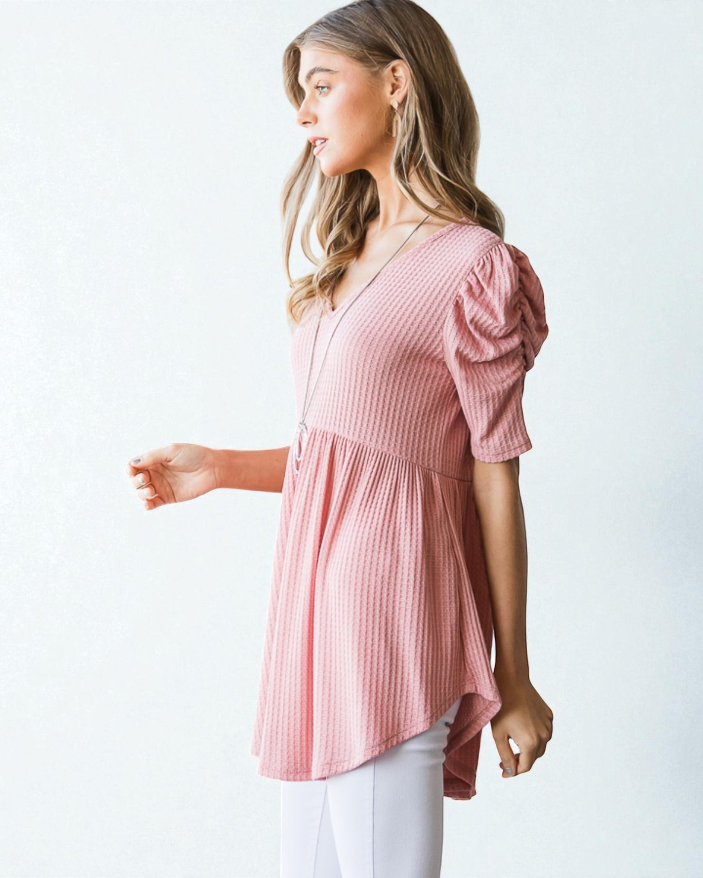 Woman wearing a pink striped top with puff sleeves on a white background
