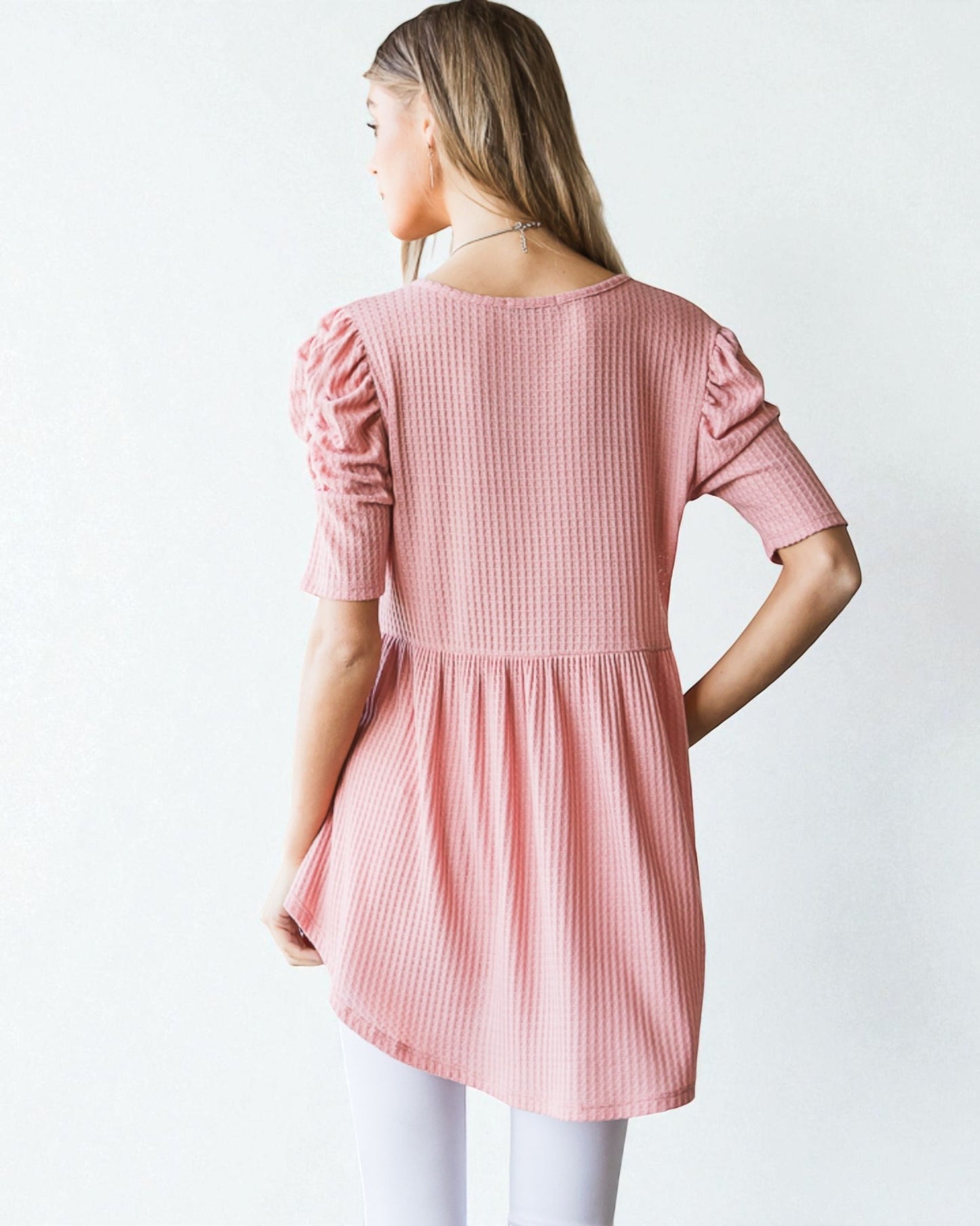 Woman wearing a pink dress with puffed sleeves on a white background