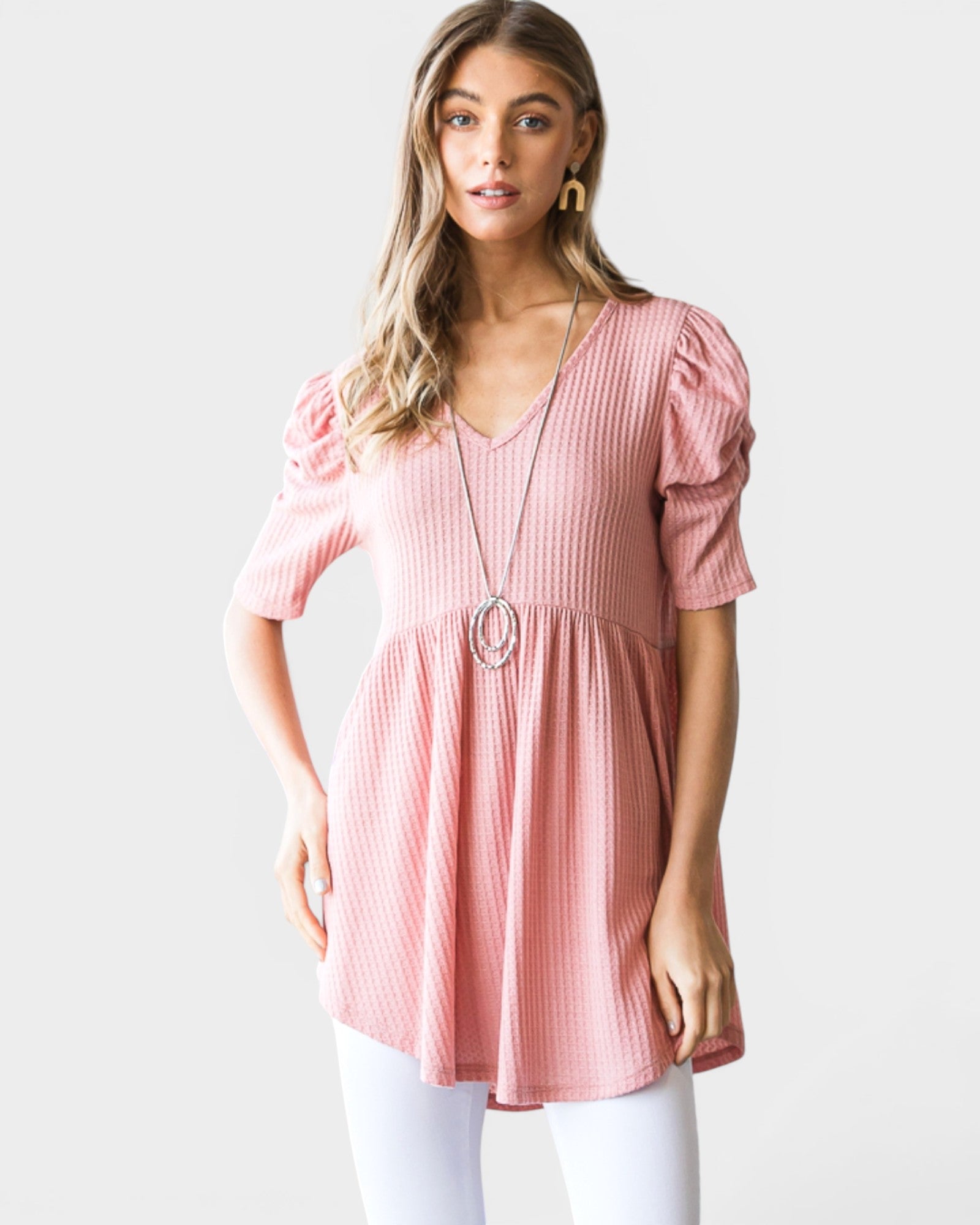 Woman wearing a pink blouse with puff sleeves on a white background