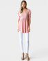Woman wearing a pink blouse and white pants on a plain background