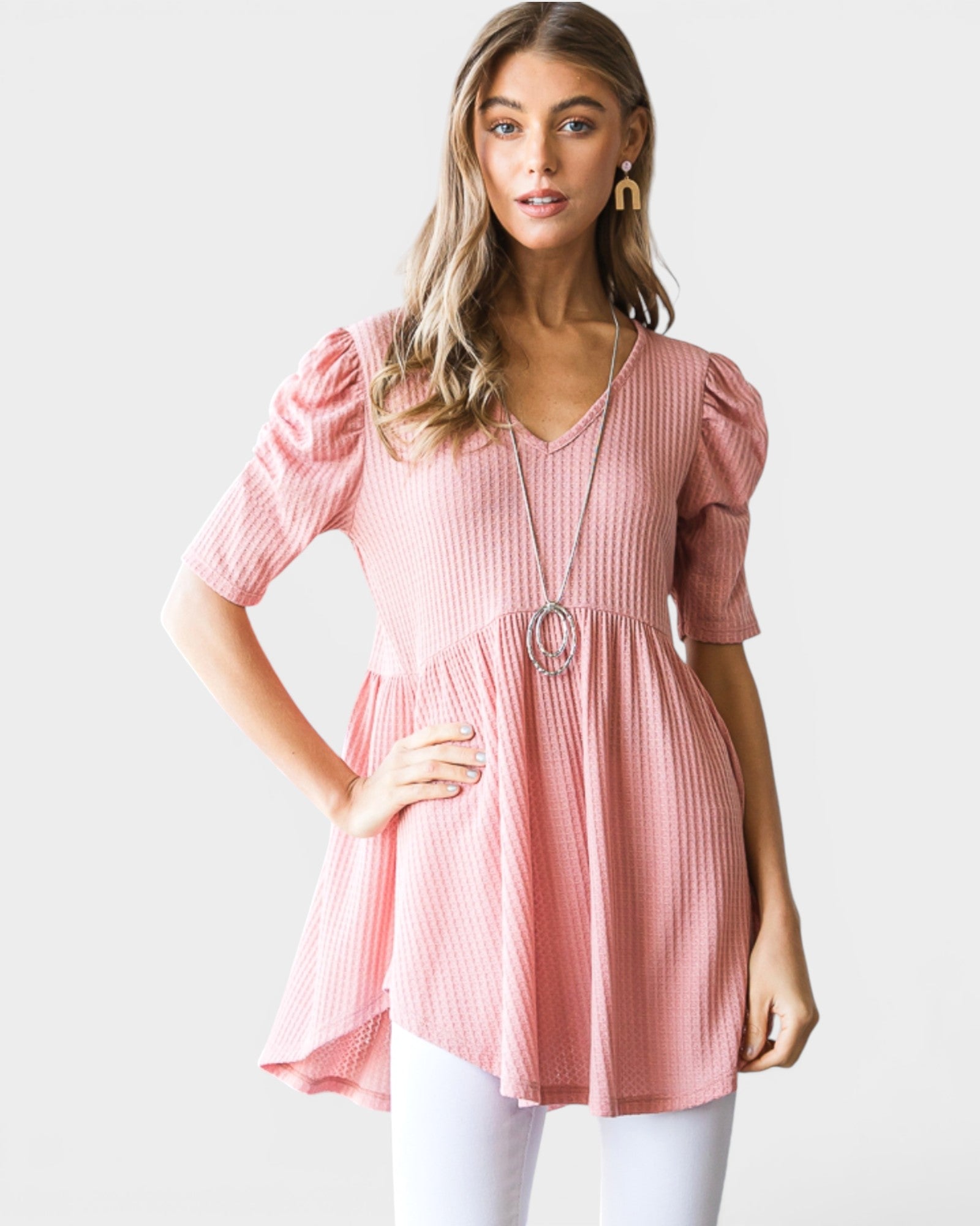 Woman wearing a pink top with puffed sleeves on a white background