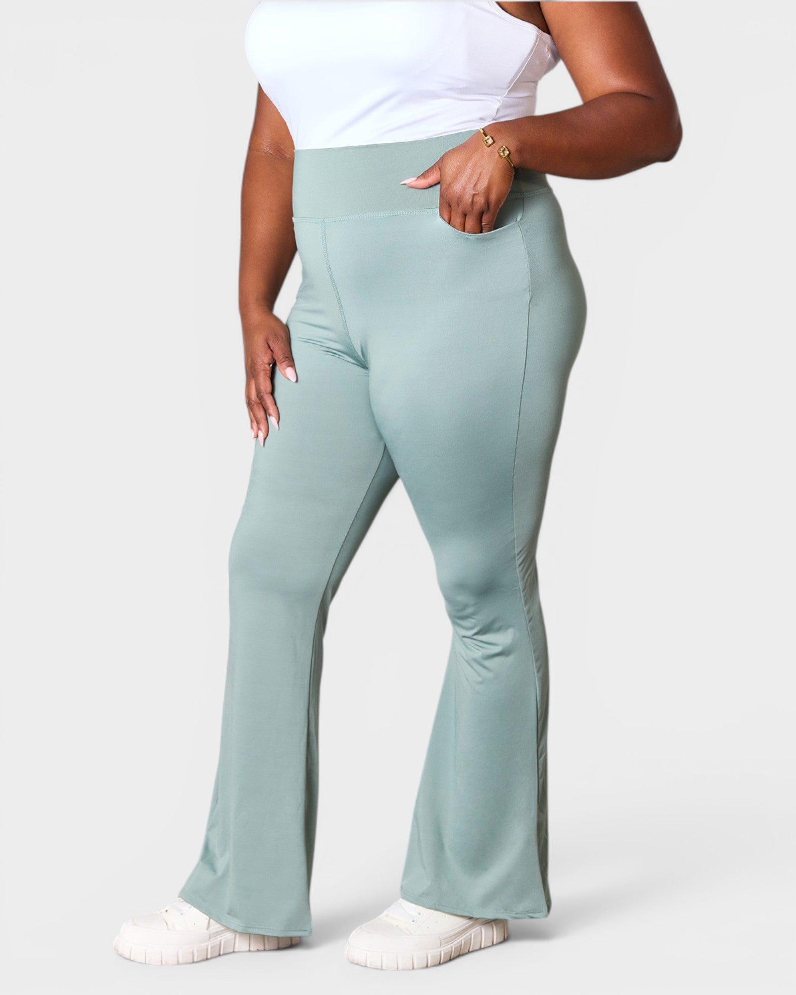 Person wearing light green flared pants on a white background
