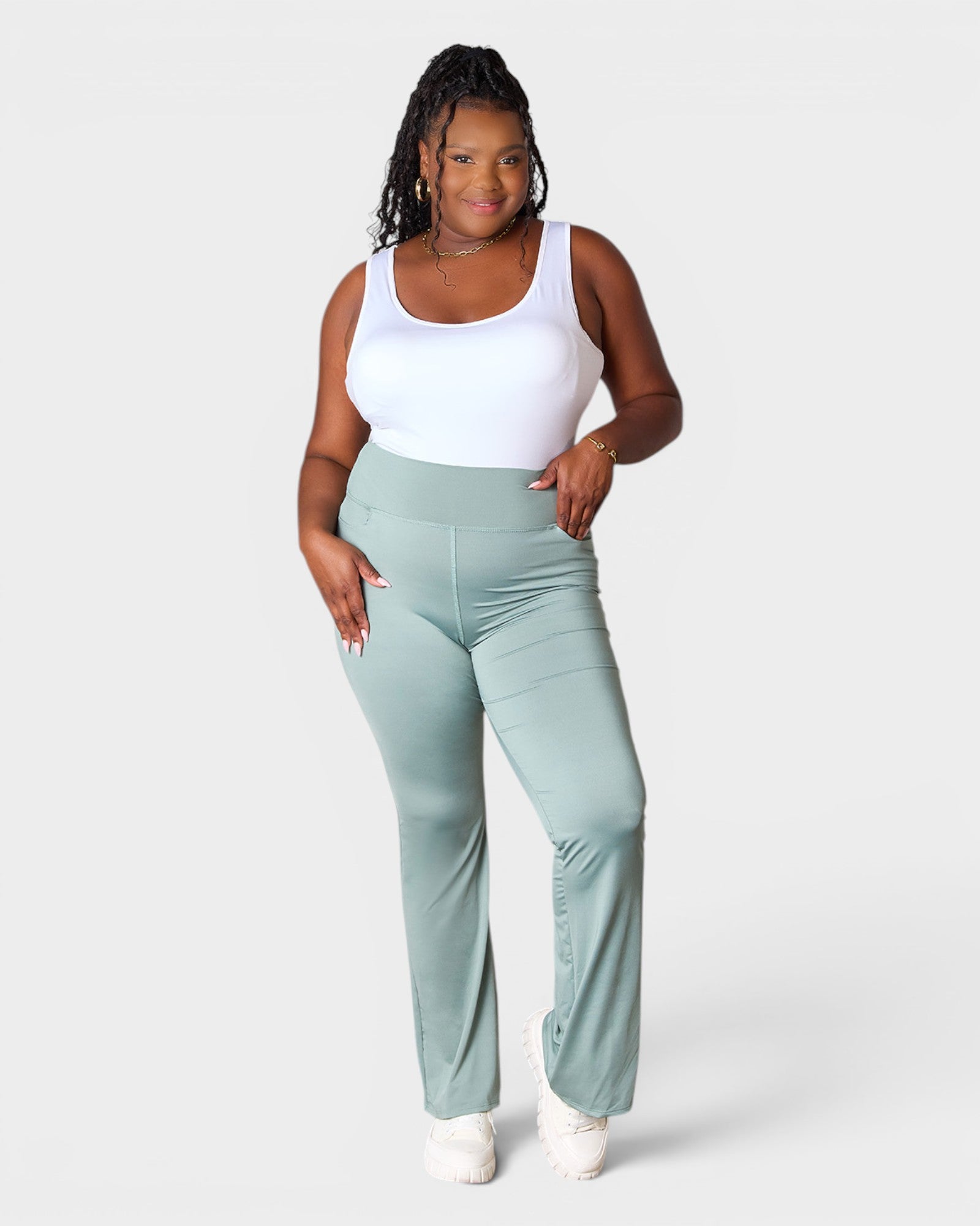 Woman wearing light green pants and a white top on a white background