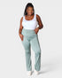 Woman wearing light green pants and a white top on a white background