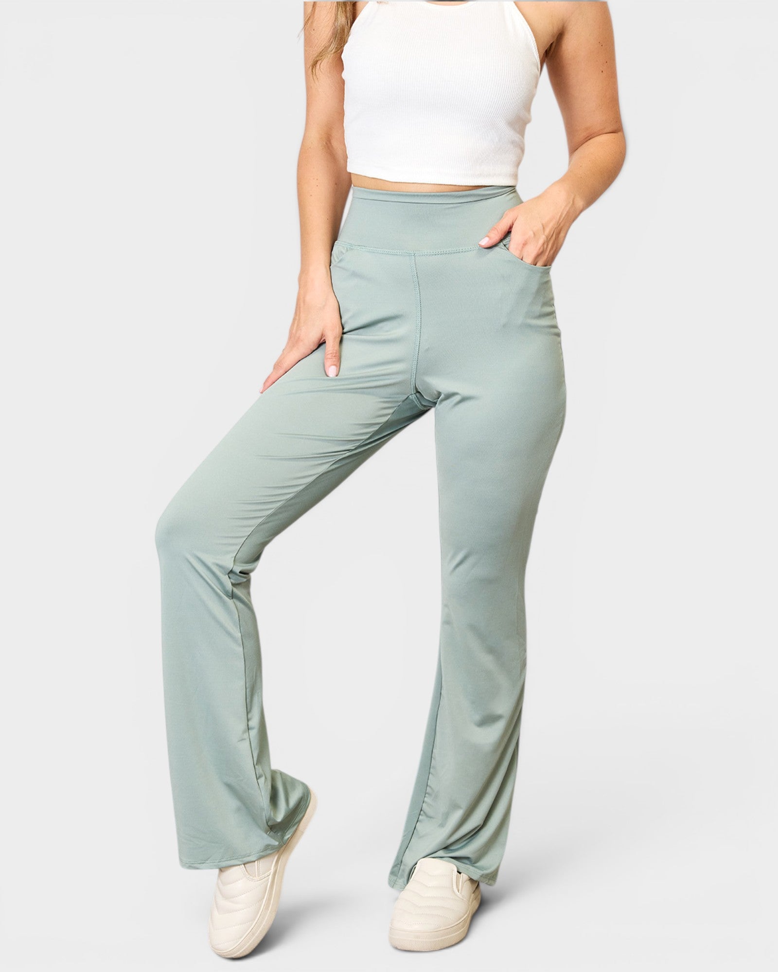 Person wearing light green pants and a white top on a plain background