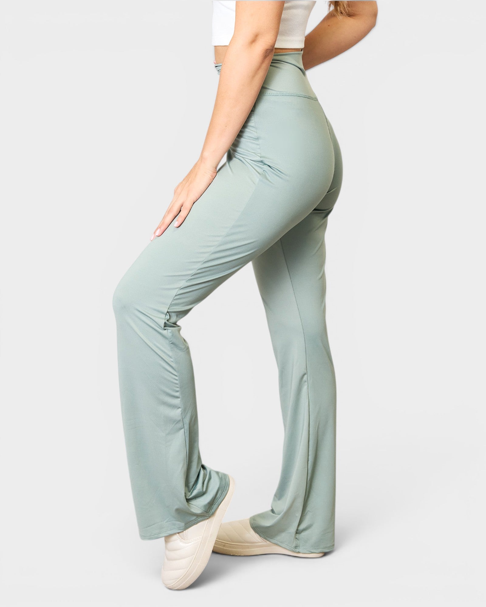 Person wearing light green high-waisted pants on a white background