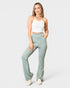 Woman wearing light green pants and a white top on a white background