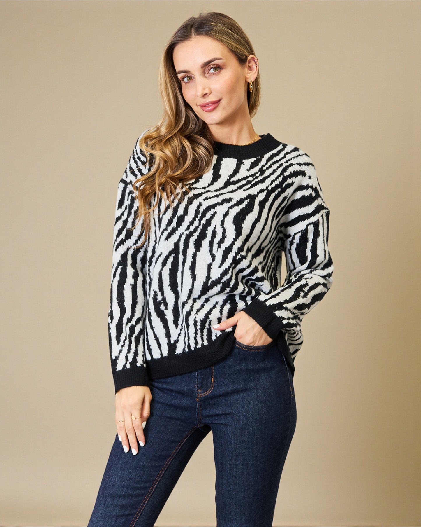 Woman wearing a zebra print sweater and jeans against a beige background