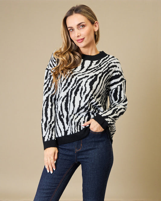 Woman wearing a zebra print sweater and jeans against a beige background