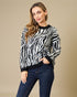 Woman wearing a zebra print sweater and jeans against a beige background