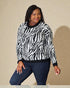 Woman wearing a zebra print sweater and jeans against a beige background