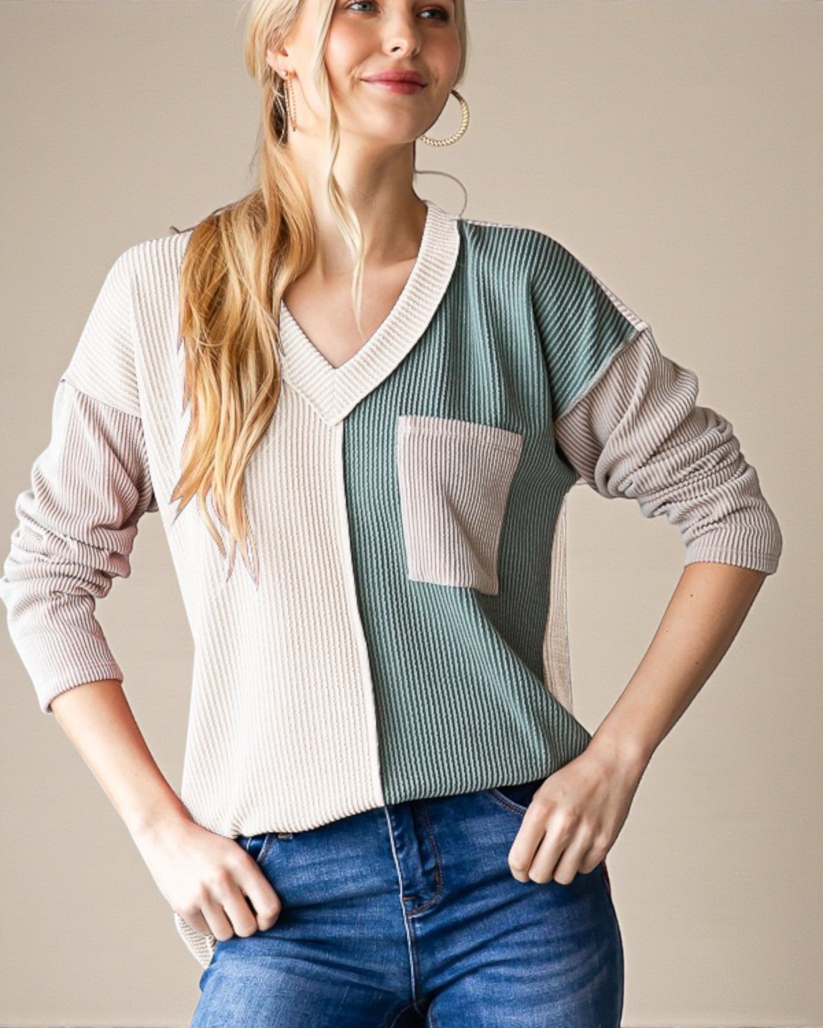 Woman wearing a color-blocked sweater with a neutral background