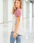 Woman wearing a two-tone shirt with a blurred indoor background