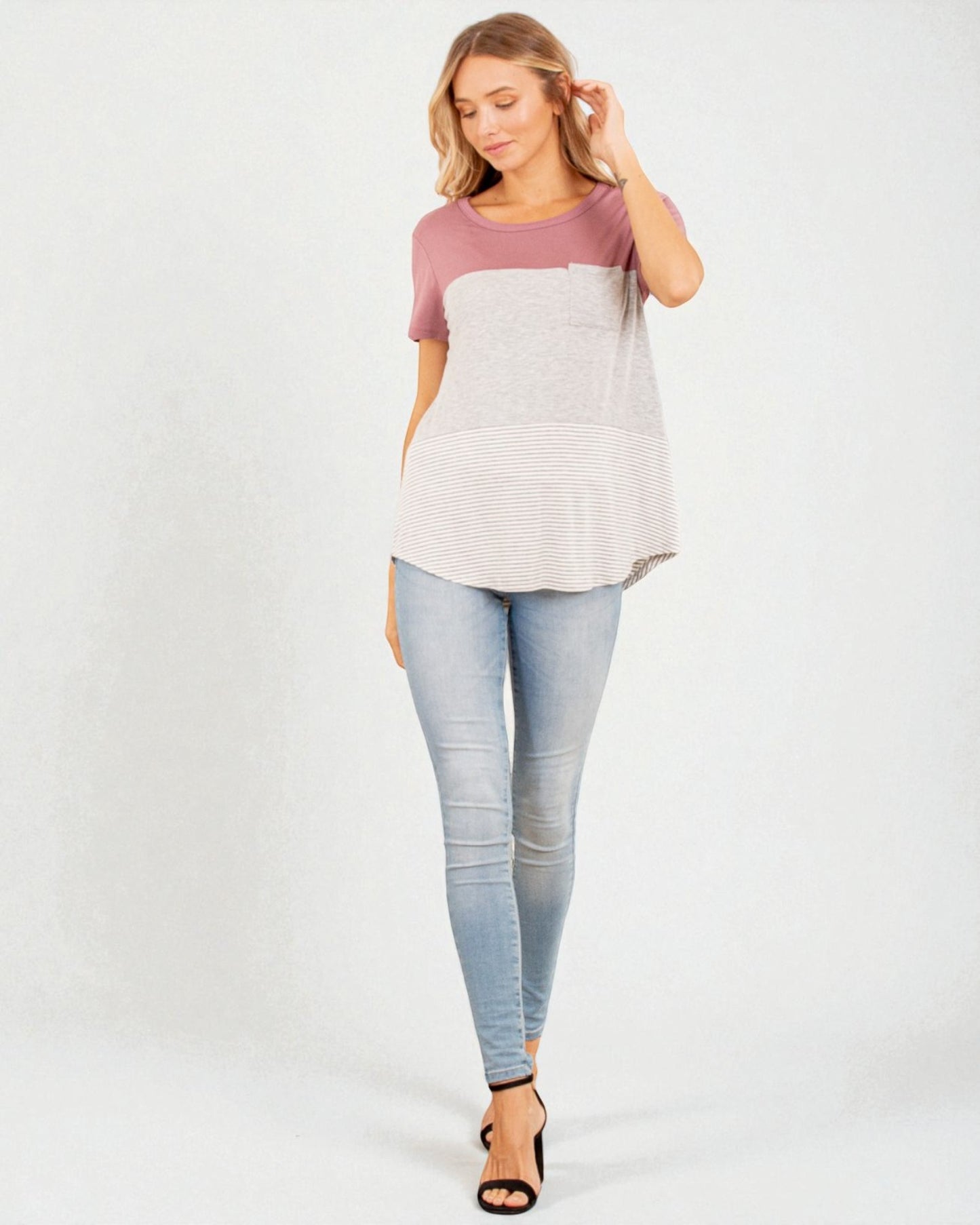 Woman wearing a two-tone top and light blue jeans on a white background