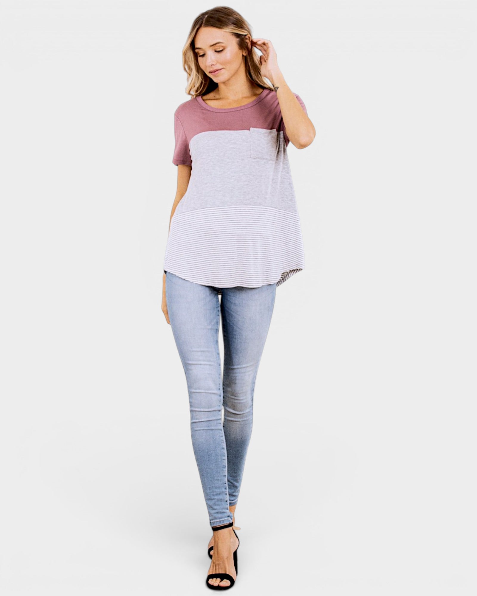 Woman wearing a two-tone top and light blue jeans on a white background