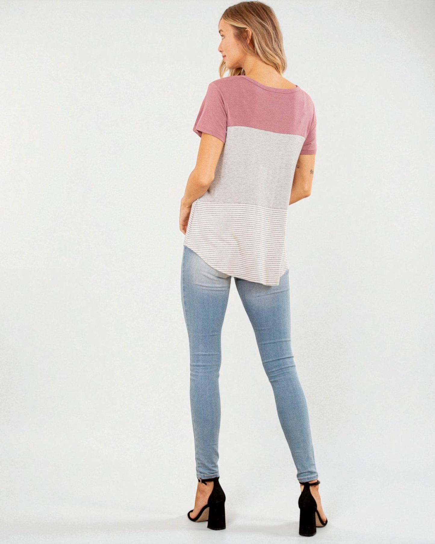 Woman wearing a two-tone shirt and light blue jeans on a white background