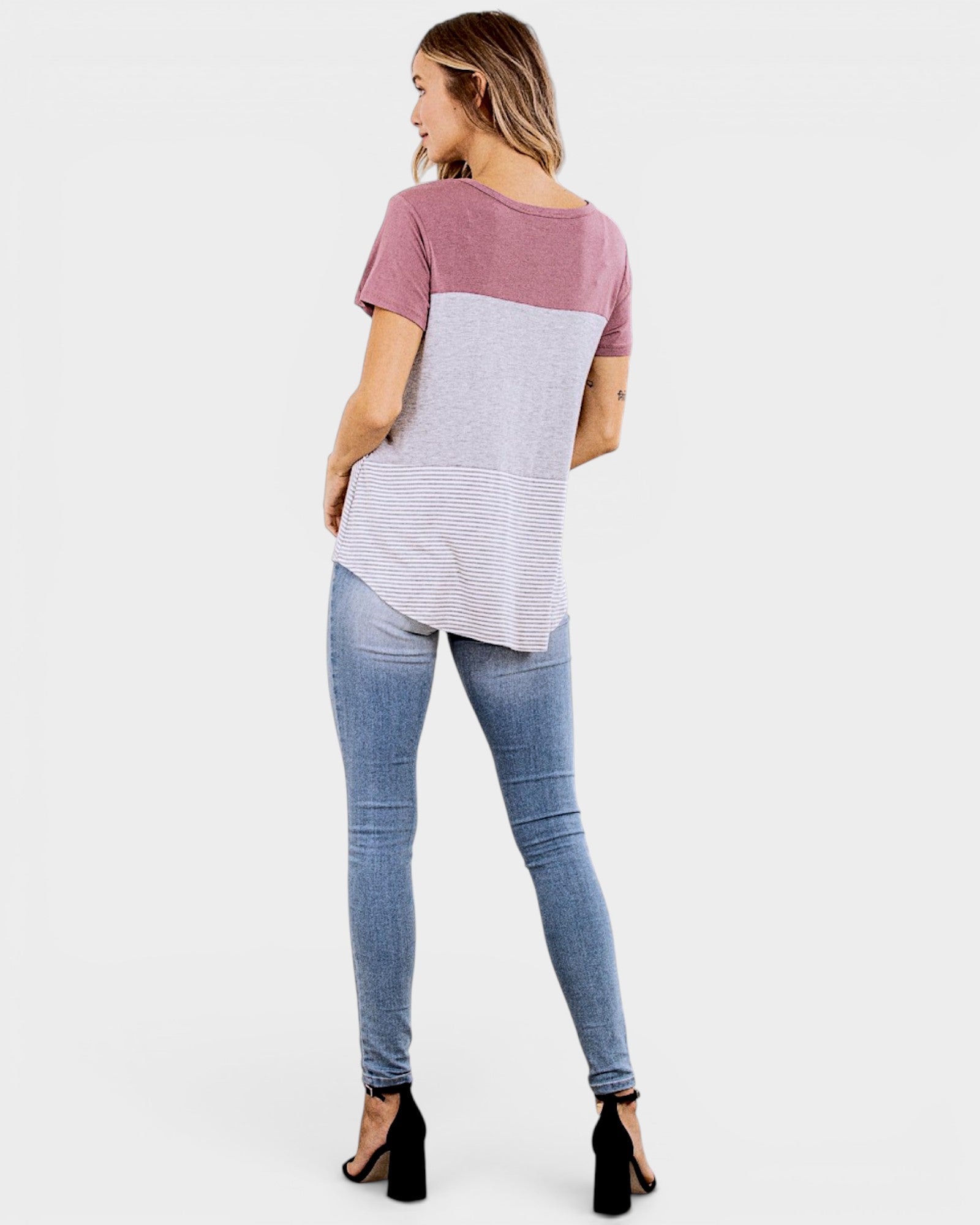 Woman wearing a two-tone shirt and jeans on a white background
