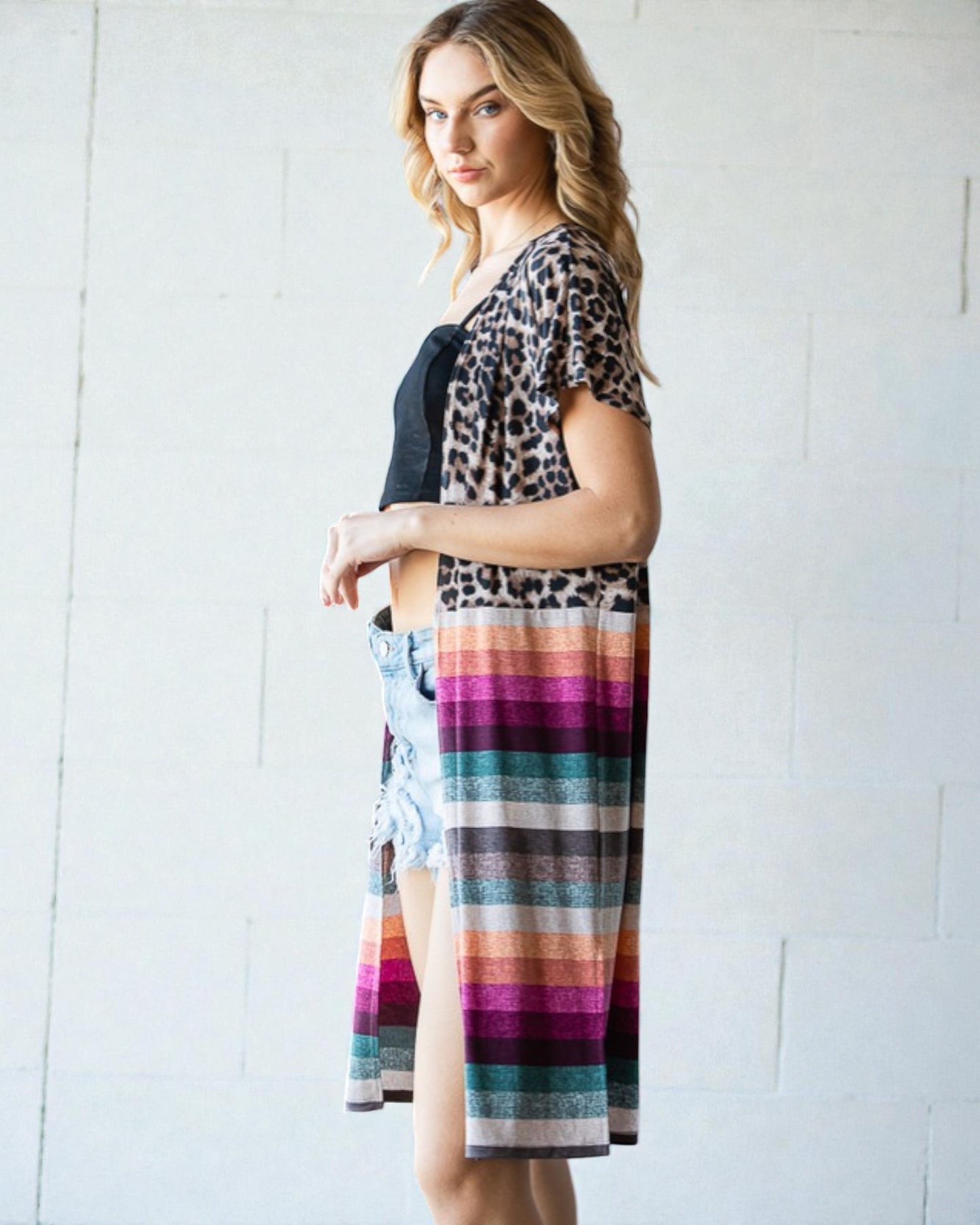 Woman wearing a leopard print top and colorful striped skirt against a white background