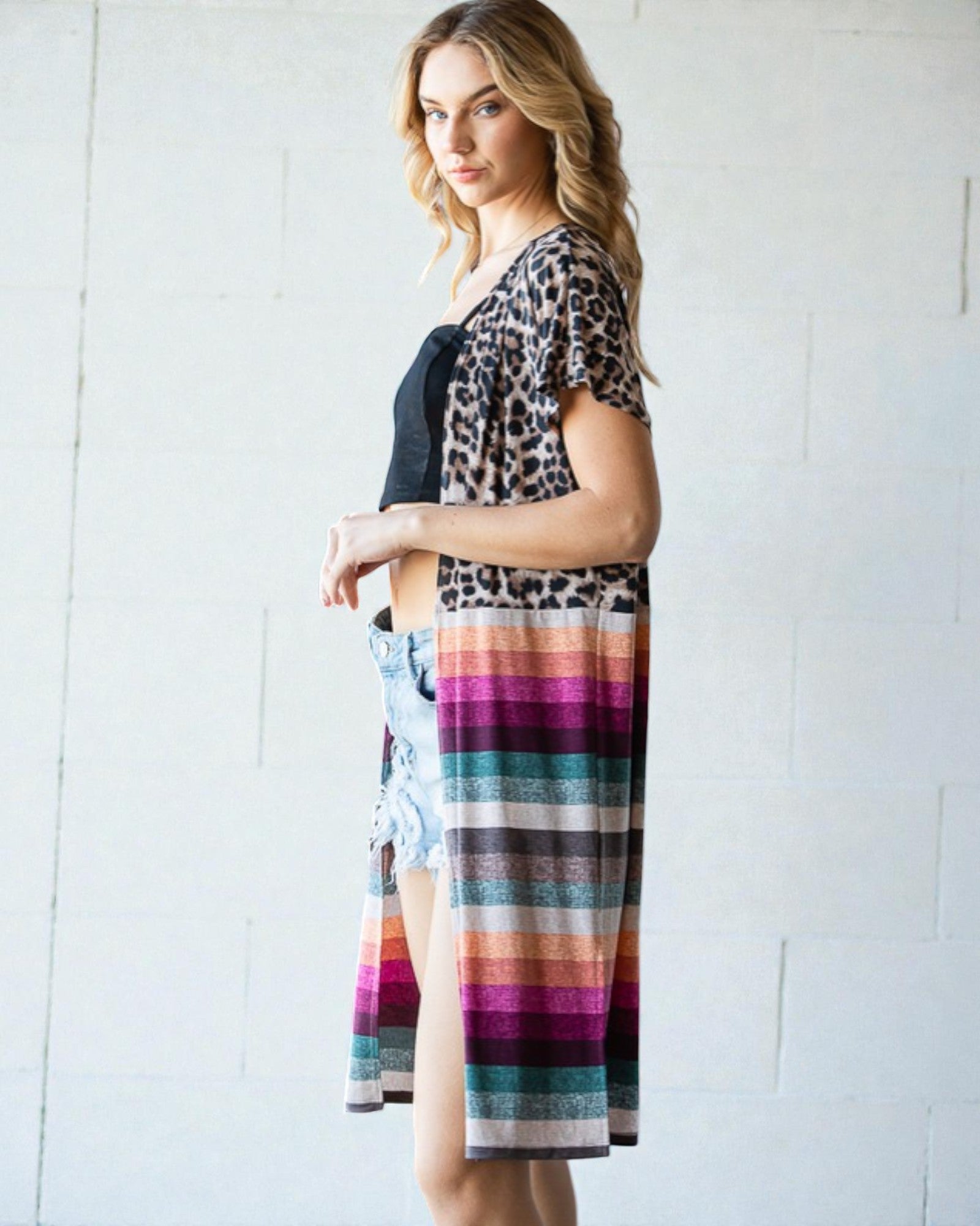 Woman wearing a leopard print top and colorful striped skirt against a white background
