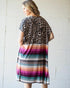 Woman wearing a dress with leopard print top and colorful striped skirt against a white tiled wall.
