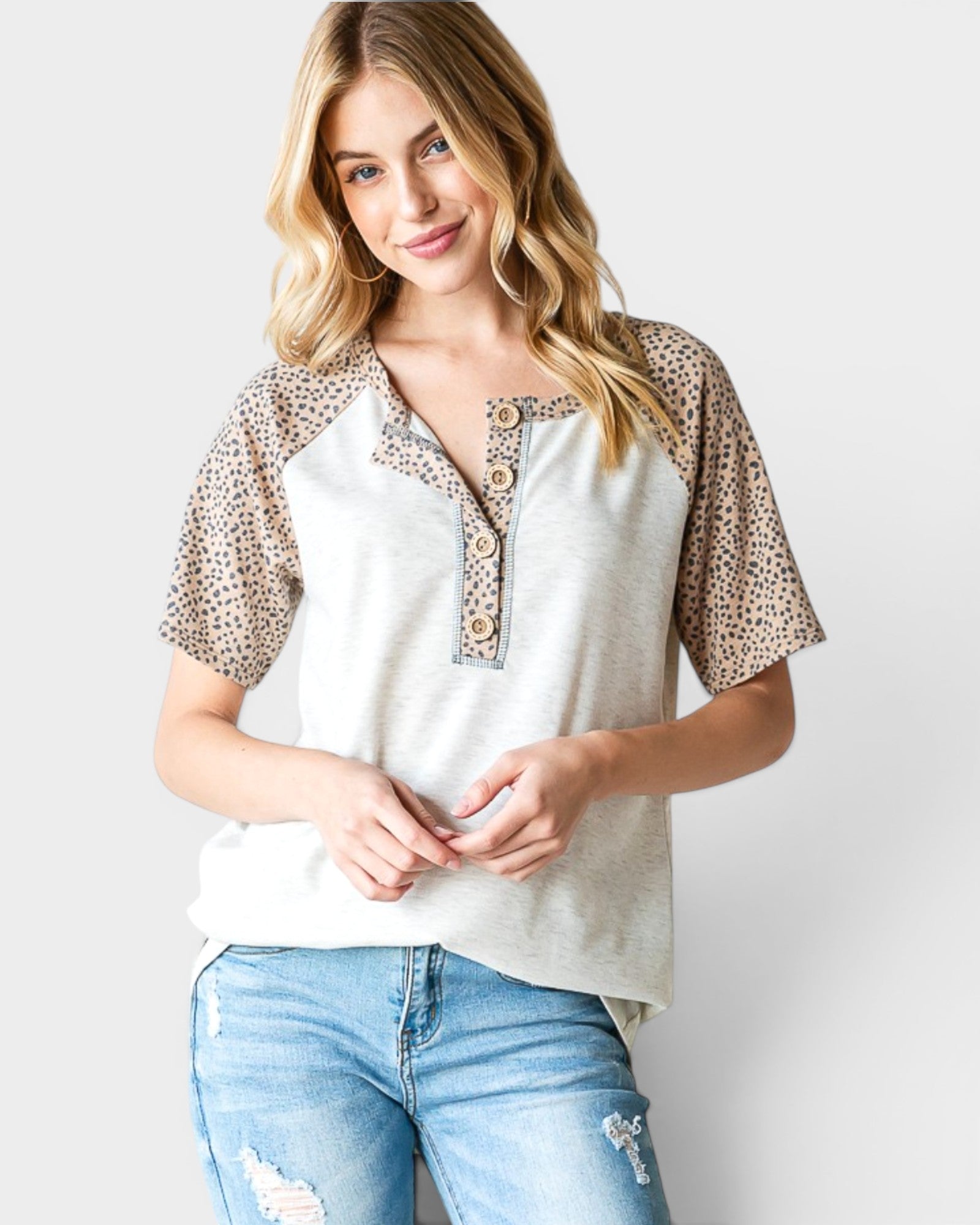 Woman wearing a white top with leopard print sleeves against a plain background