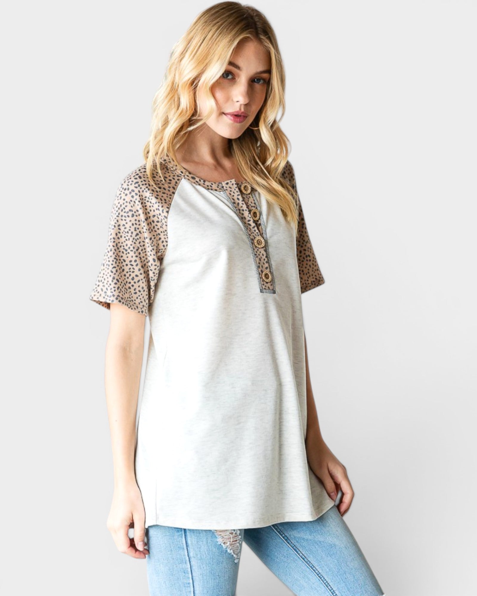 Woman wearing a white top with leopard print accents on a plain background