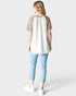 Person wearing a white tunic with brown sleeves and light blue jeans on a white background