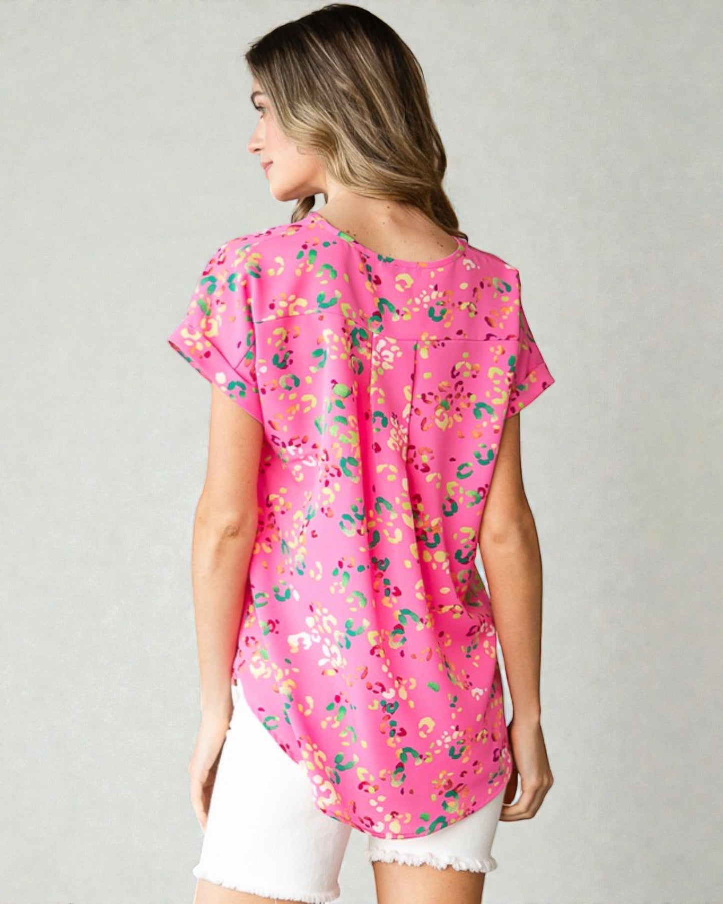 Woman wearing a pink floral blouse on a plain background