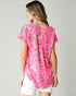 Woman wearing a pink floral blouse on a plain background