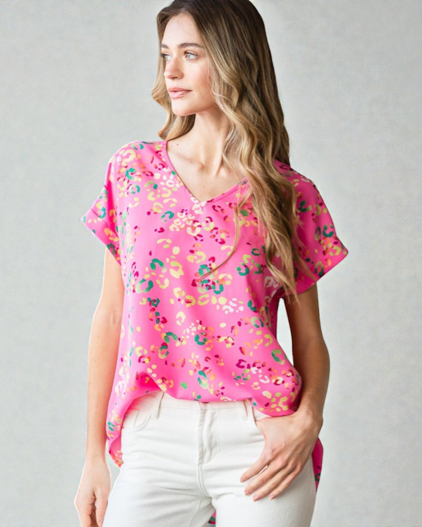 Woman wearing a pink blouse with colorful patterns on a gray background