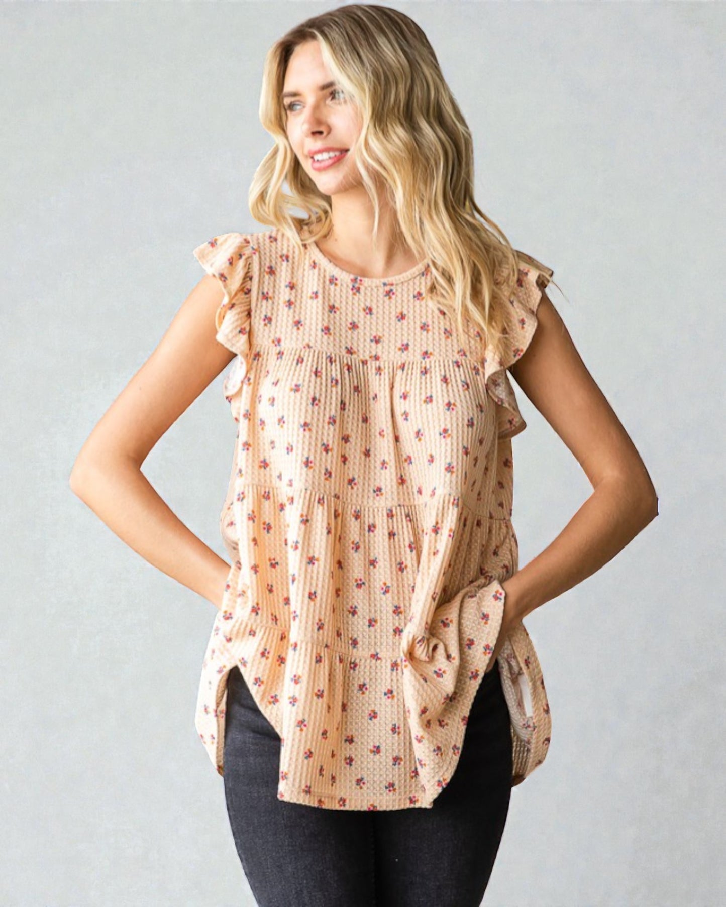 Woman wearing a patterned blouse with ruffled sleeves against a plain background