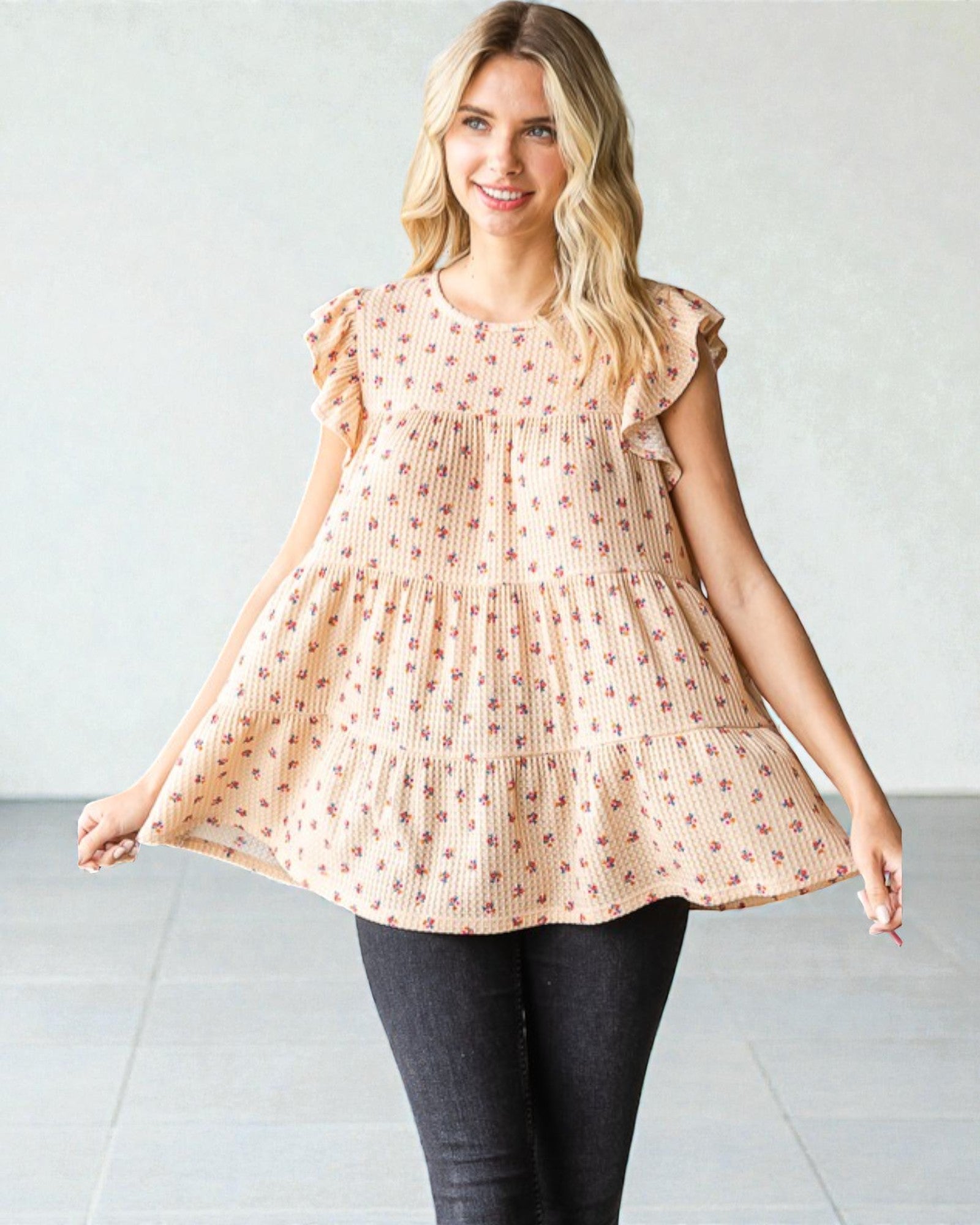 Woman wearing a peach-colored dress with ruffled sleeves against a white background