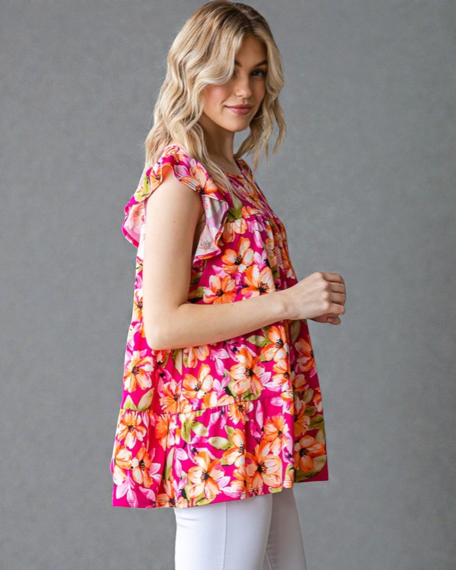Woman wearing a colorful floral sleeveless top against a gray background