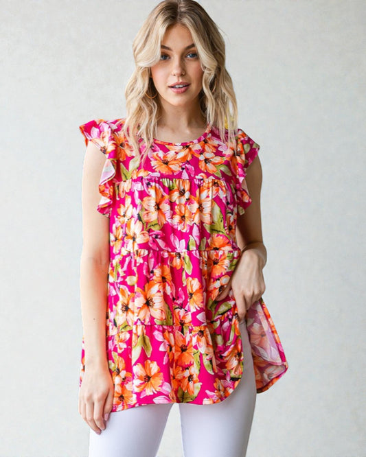 Woman wearing a colorful floral blouse against a plain background