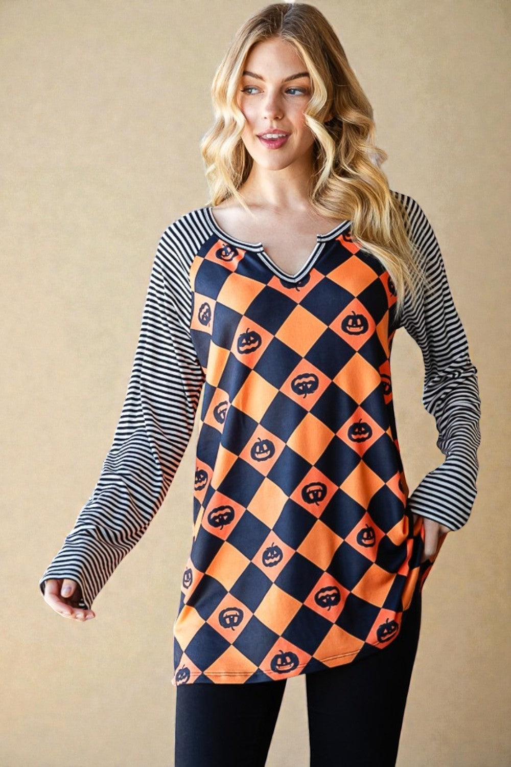 Woman wearing a Halloween-themed dress with pumpkins and ghosts on a beige background