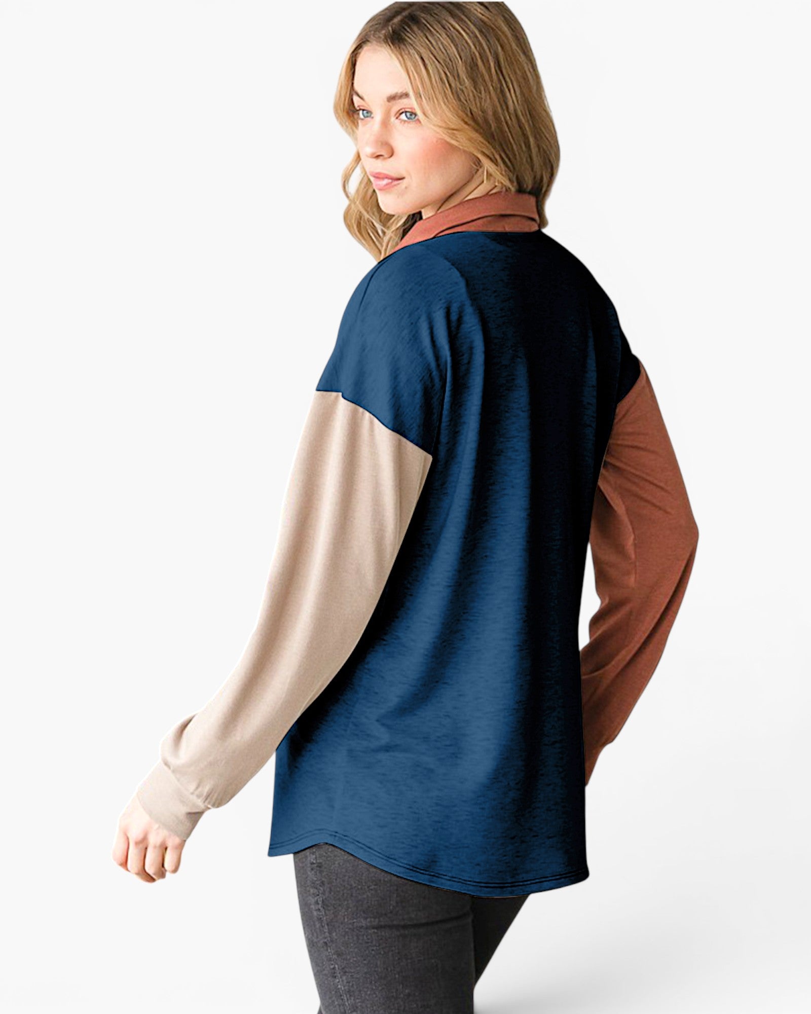 A woman shown from the back wearing a color-blocked long-sleeve top with a navy blue main body, beige sleeves, and rust brown sleeves, paired with dark gray pants against a clean white background.
