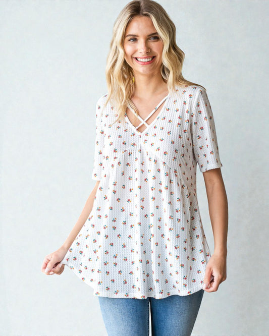 Woman wearing a white floral blouse with a plain background